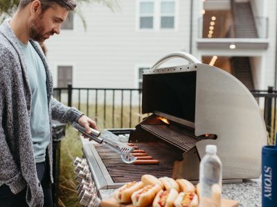 a man is cooking hot dogs on a grill at The Story Lake Gibson